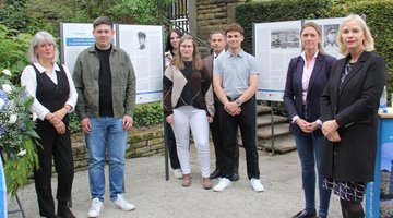 Personengruppe vor und neben einigen Schautafeln. Die Übergabe der Geschichts- und Erinnerungstafeln auf der Kriegsgräberstätte Würzburg - Hauptfriedhof