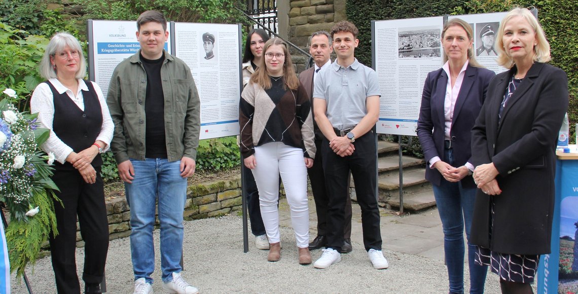 Personengruppe vor und neben einigen Schautafeln. Die Übergabe der Geschichts- und Erinnerungstafeln auf der Kriegsgräberstätte Würzburg - Hauptfriedhof